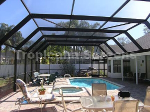 A beautiful patio with a pool, patio furniture, and pool enclosure